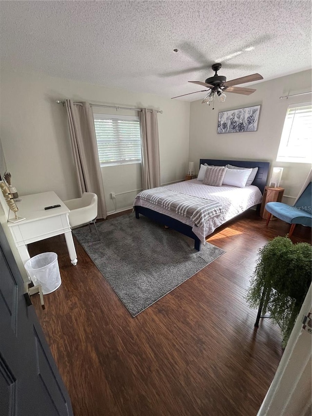 bedroom featuring ceiling fan, dark wood-type flooring, and a textured ceiling