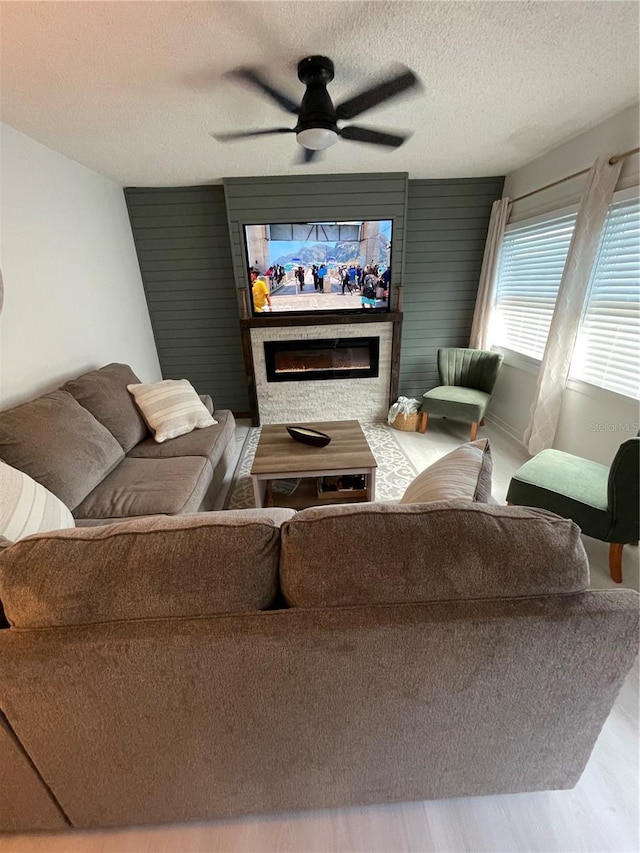 living room with ceiling fan, a textured ceiling, and wood-type flooring