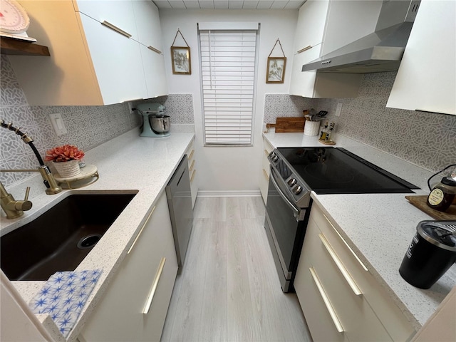 kitchen featuring tasteful backsplash, sink, wall chimney exhaust hood, stainless steel appliances, and light hardwood / wood-style flooring