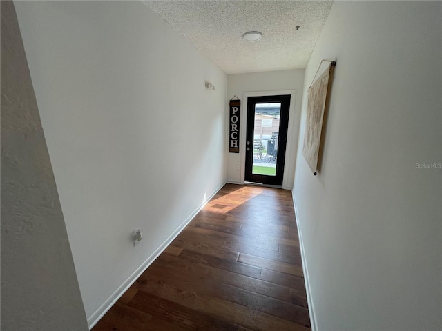 corridor with a textured ceiling and dark hardwood / wood-style floors