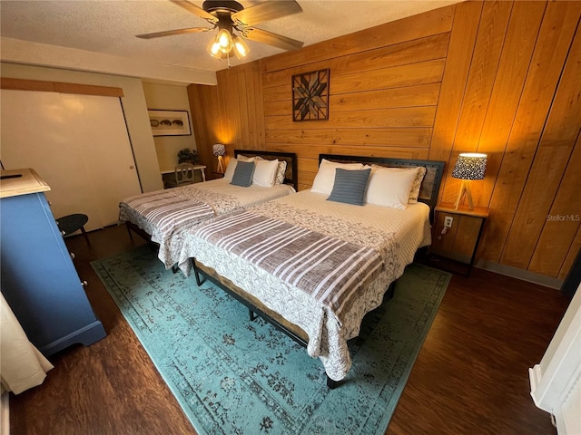 bedroom with a textured ceiling, wooden walls, dark hardwood / wood-style floors, and ceiling fan