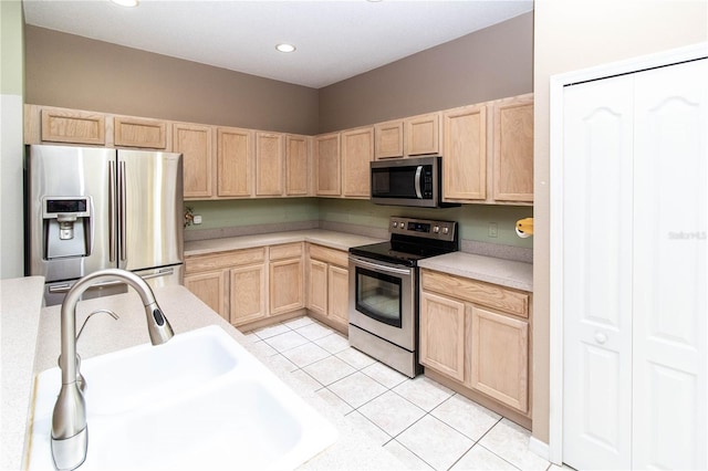 kitchen featuring light brown cabinetry, light tile patterned floors, stainless steel appliances, and sink