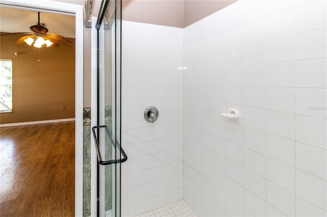 bathroom with ceiling fan, an enclosed shower, and hardwood / wood-style floors