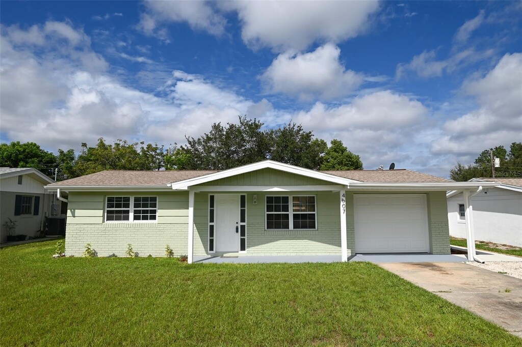 single story home featuring a garage, covered porch, and a front yard