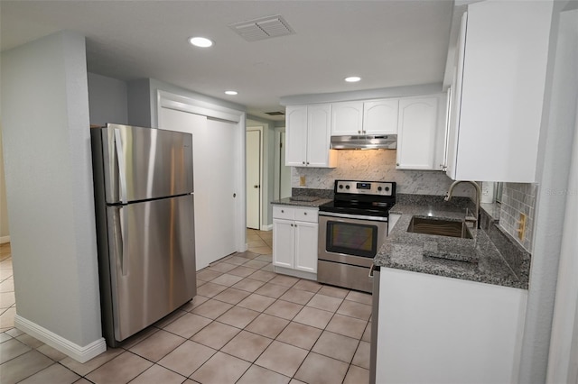 kitchen with dark stone countertops, white cabinets, sink, appliances with stainless steel finishes, and light tile patterned flooring