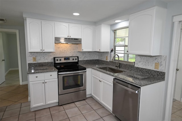 kitchen featuring white cabinets, backsplash, light tile patterned floors, appliances with stainless steel finishes, and sink