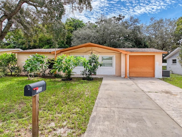 single story home with a garage, a front yard, and central air condition unit