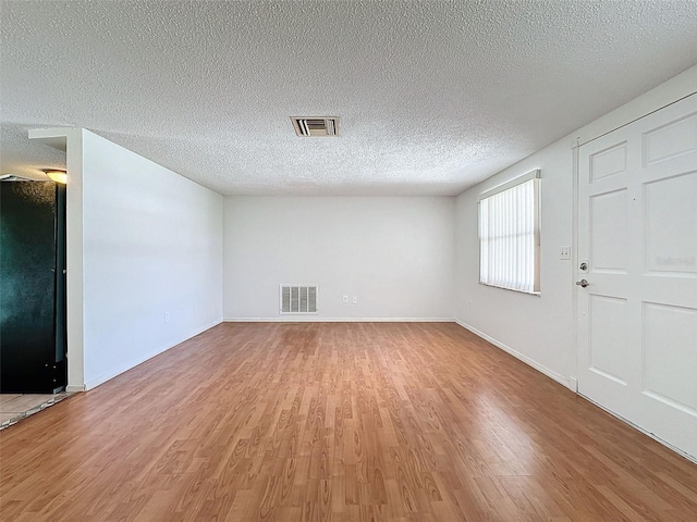 unfurnished room with a textured ceiling and hardwood / wood-style flooring