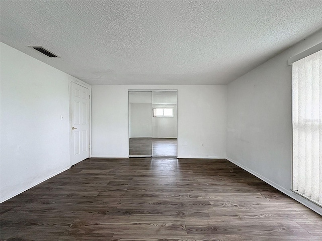 unfurnished room with a textured ceiling and dark wood-type flooring