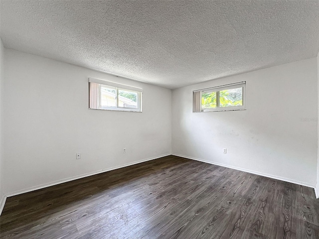 spare room featuring a textured ceiling and dark hardwood / wood-style floors