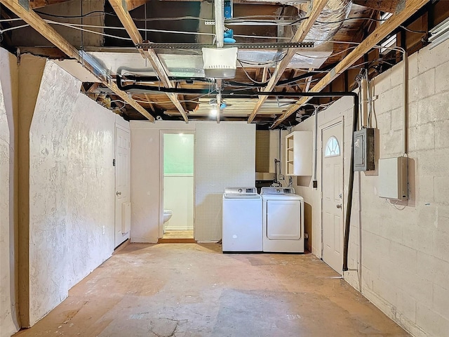 basement with electric panel and washing machine and clothes dryer