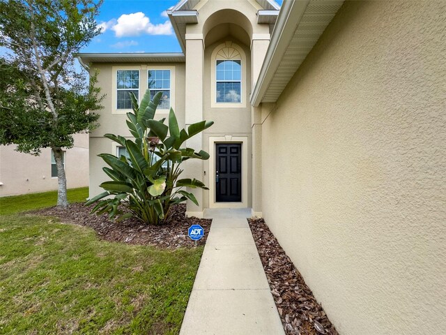 view of exterior entry with a yard