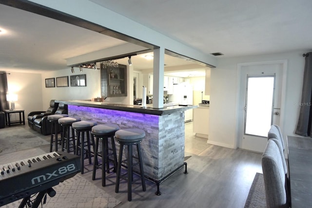 bar with hardwood / wood-style floors and white fridge