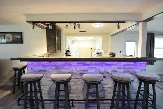 bar featuring white cabinets, white refrigerator, and dark wood-type flooring