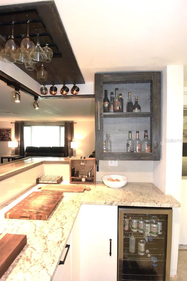 bar featuring light stone counters, wine cooler, and white cabinetry