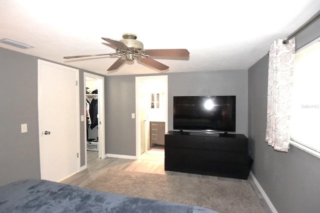 bedroom with a spacious closet, a closet, light hardwood / wood-style floors, and ceiling fan