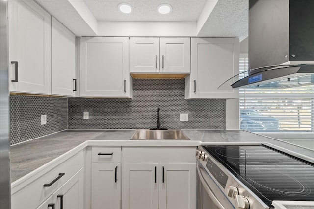 kitchen featuring island exhaust hood, stainless steel electric range, decorative backsplash, white cabinets, and sink