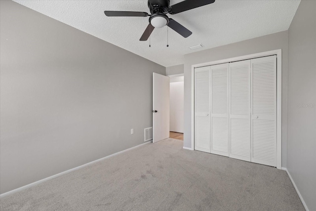 unfurnished bedroom with light carpet, a closet, ceiling fan, and a textured ceiling