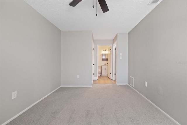 unfurnished room with a textured ceiling, ceiling fan, and light colored carpet