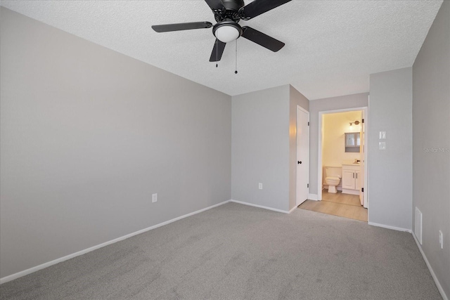 spare room featuring ceiling fan, light carpet, and a textured ceiling