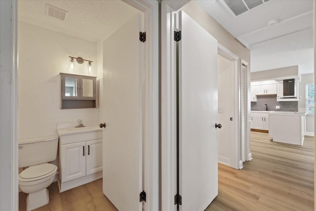 bathroom with toilet, vanity, hardwood / wood-style floors, and tasteful backsplash