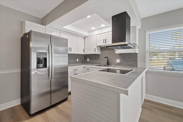 kitchen featuring sink, white cabinets, kitchen peninsula, stainless steel fridge with ice dispenser, and range hood