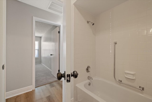 bathroom with a textured ceiling, hardwood / wood-style floors, and  shower combination