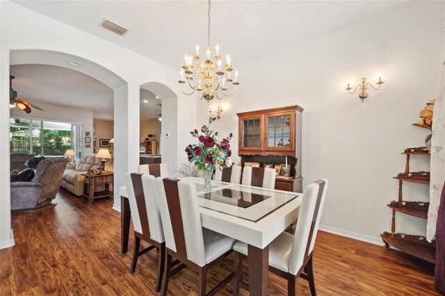 dining area with ceiling fan with notable chandelier and dark hardwood / wood-style floors