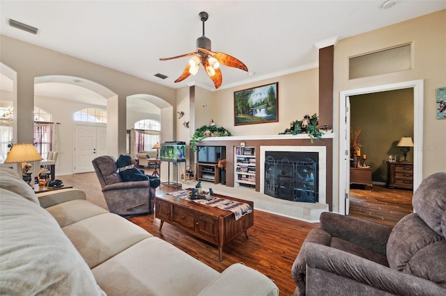 living room featuring wood-type flooring, ceiling fan, and crown molding