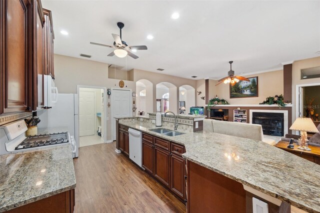 kitchen with white appliances, light stone countertops, ceiling fan, light hardwood / wood-style floors, and sink