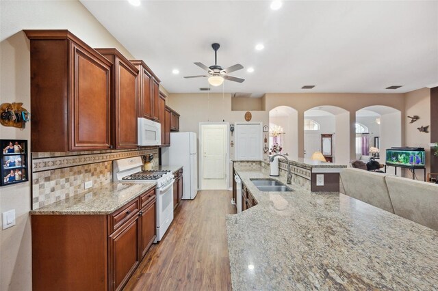 kitchen with ceiling fan, sink, white appliances, light stone countertops, and hardwood / wood-style floors