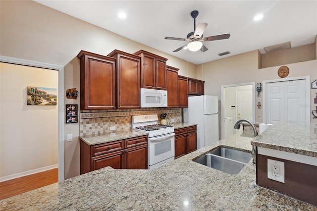 kitchen with wood-type flooring, sink, white appliances, light stone countertops, and ceiling fan