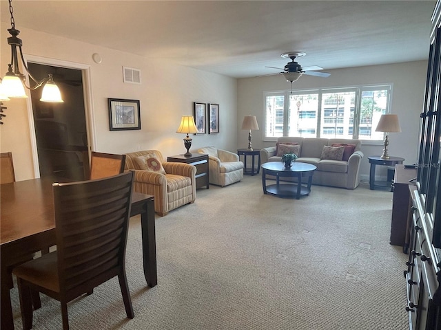 carpeted living room with ceiling fan with notable chandelier