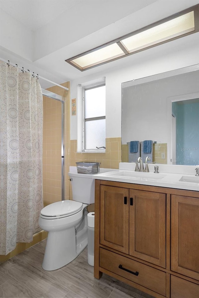 bathroom with tile walls, vanity, wood-type flooring, toilet, and a shower with curtain