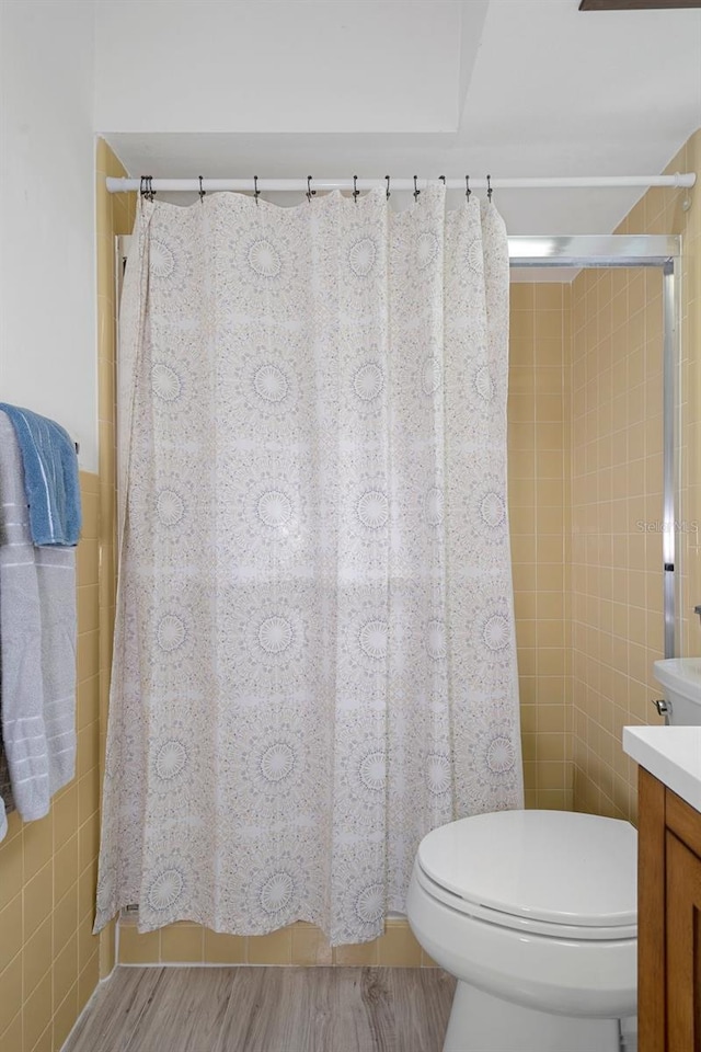 bathroom featuring vanity, hardwood / wood-style flooring, a shower with curtain, tile walls, and toilet