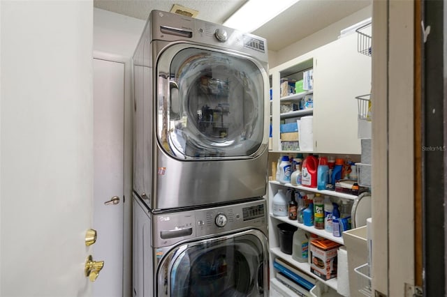 laundry room featuring a textured ceiling and stacked washing maching and dryer