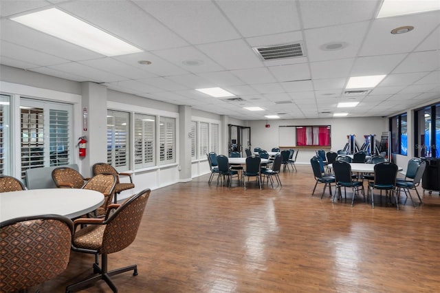 dining room with dark wood-type flooring and a paneled ceiling