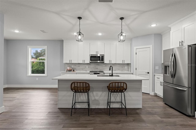 kitchen featuring an island with sink, stainless steel appliances, sink, and white cabinetry