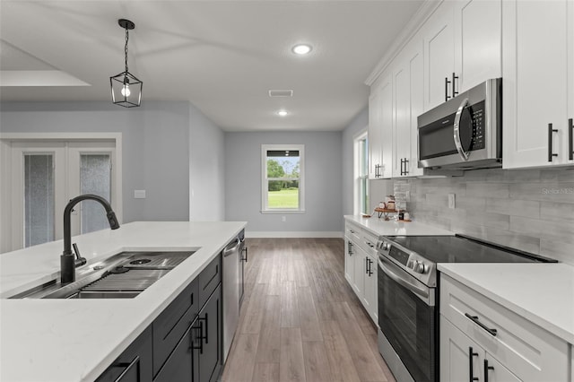 kitchen with pendant lighting, light hardwood / wood-style floors, sink, white cabinetry, and appliances with stainless steel finishes