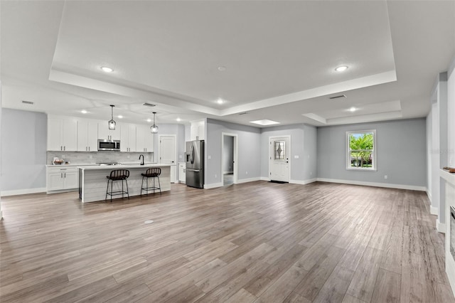 unfurnished living room with a raised ceiling and light hardwood / wood-style floors