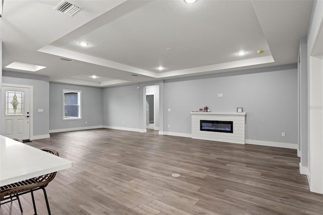 living room with wood-type flooring and a tray ceiling