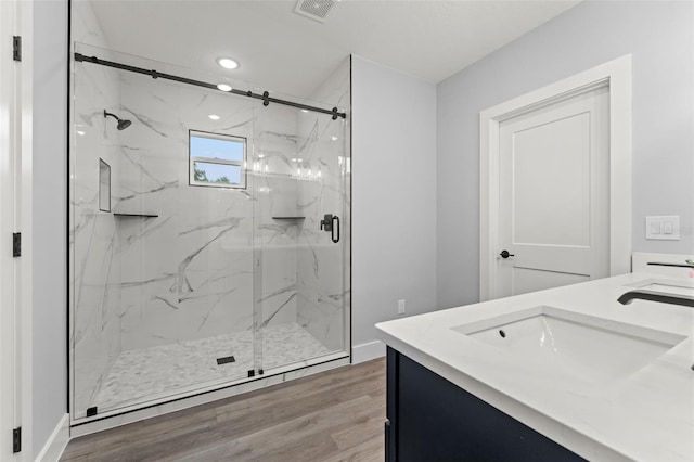 bathroom featuring a shower with shower door, hardwood / wood-style flooring, and vanity