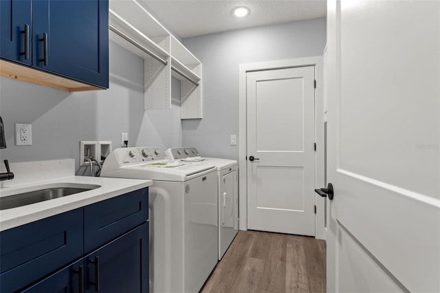 washroom with independent washer and dryer, sink, light hardwood / wood-style flooring, and cabinets