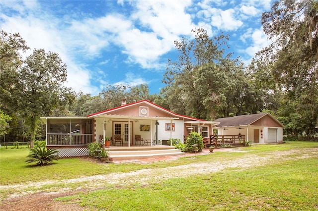 exterior space featuring a garage, a porch, a lawn, and an outbuilding