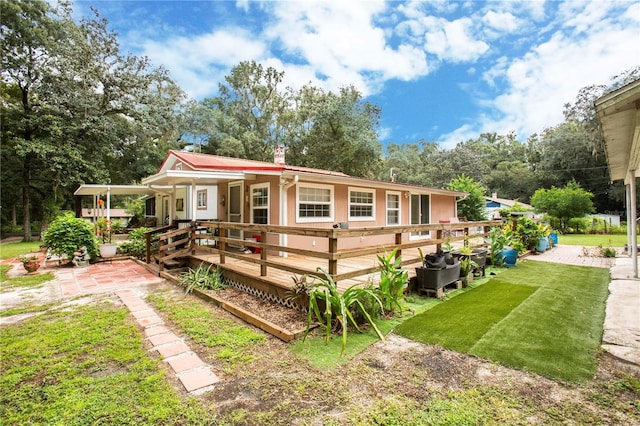 rear view of property featuring a lawn and a wooden deck