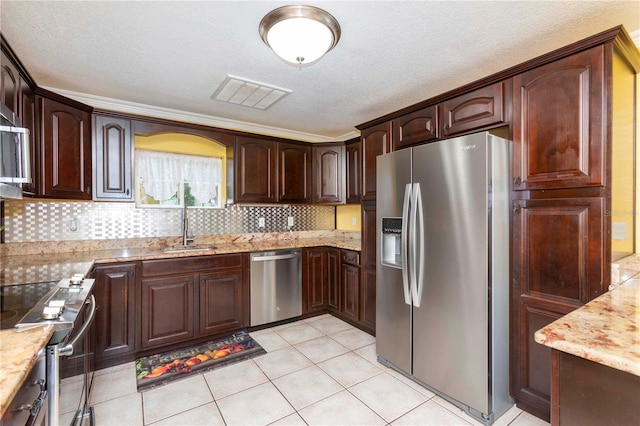 kitchen with light stone counters, a textured ceiling, decorative backsplash, appliances with stainless steel finishes, and light tile patterned floors