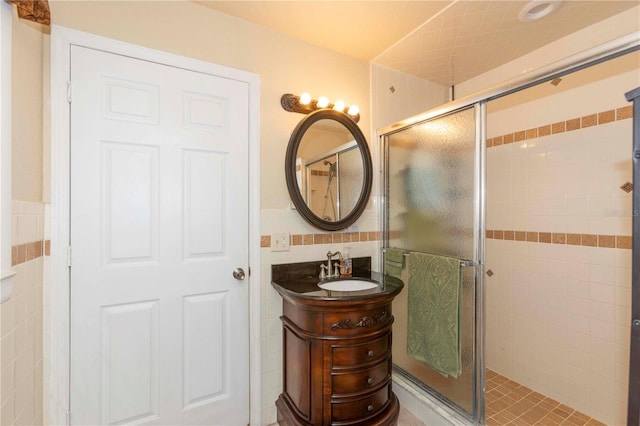 bathroom featuring tile walls, a shower with door, and vanity