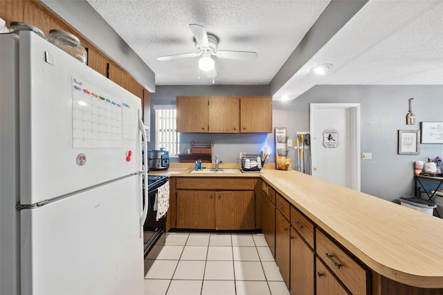 kitchen with ceiling fan, kitchen peninsula, white fridge, and sink