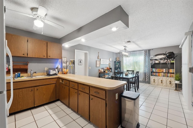 kitchen featuring ceiling fan with notable chandelier, kitchen peninsula, light tile patterned flooring, and a textured ceiling