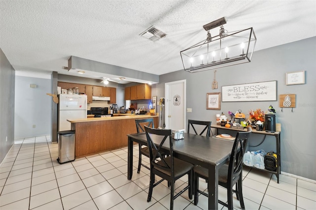 tiled dining area with ceiling fan and a textured ceiling